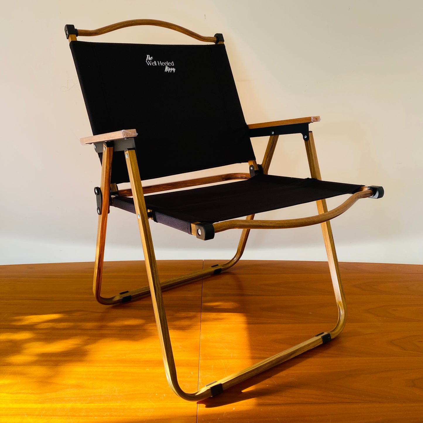 A side-view of the black, foldable, portable, luxury safari chair by The Well Heeled Hippy Store